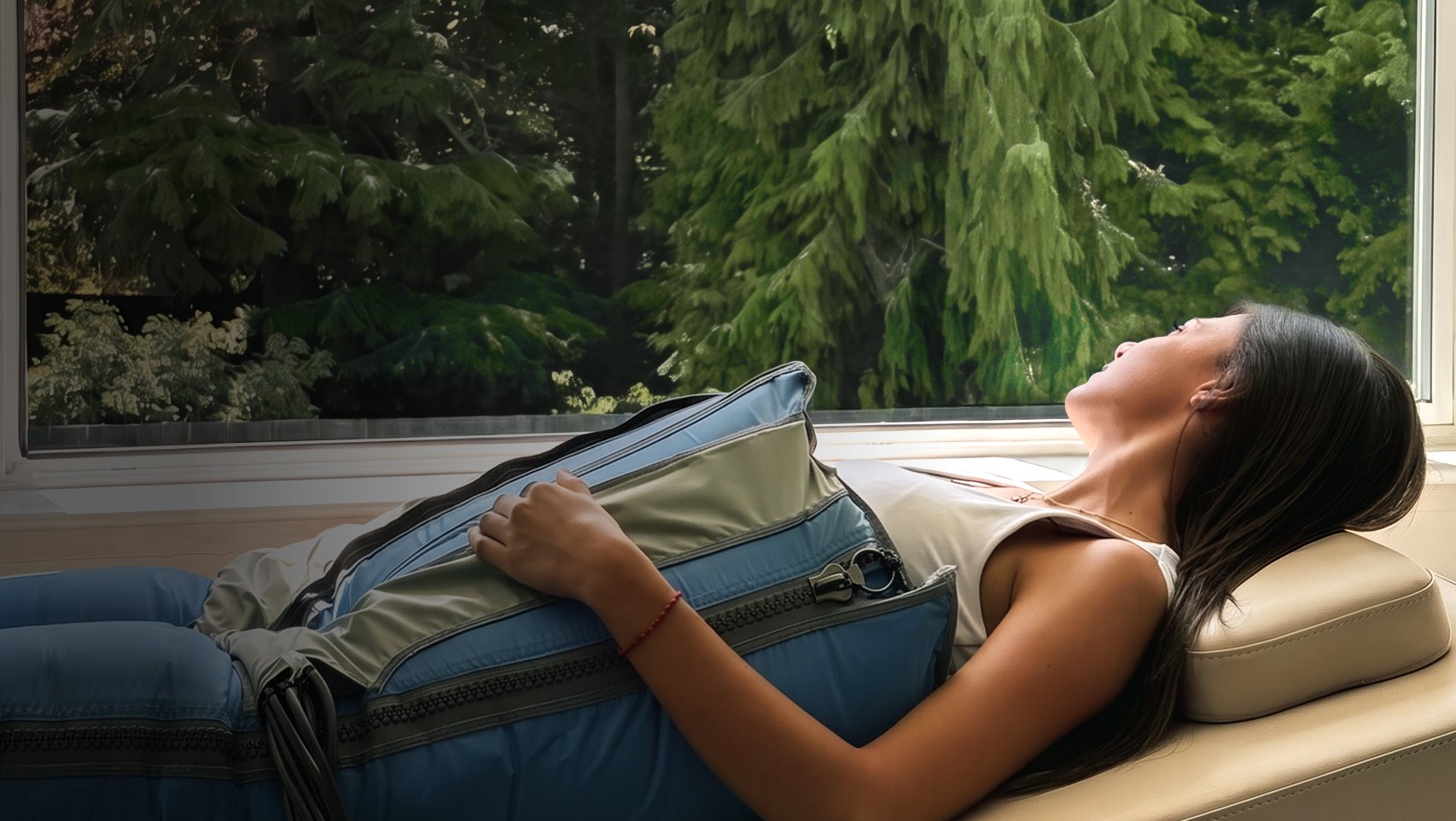 A client relaxing during lymphatic compression therapy by a window overlooking the trees