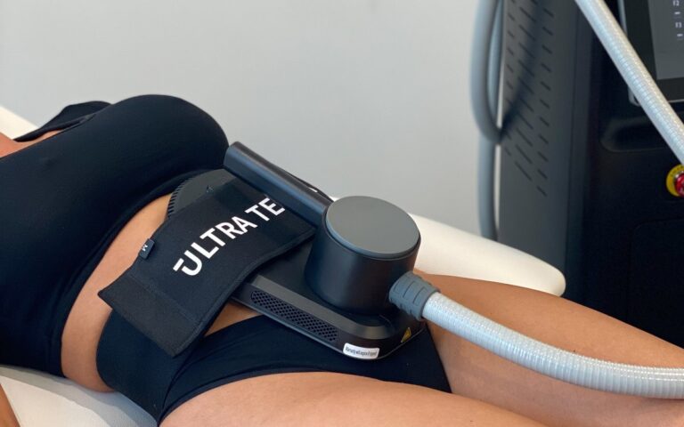An Ultra Tesla EMS applicator strapped to a client’s abdomen